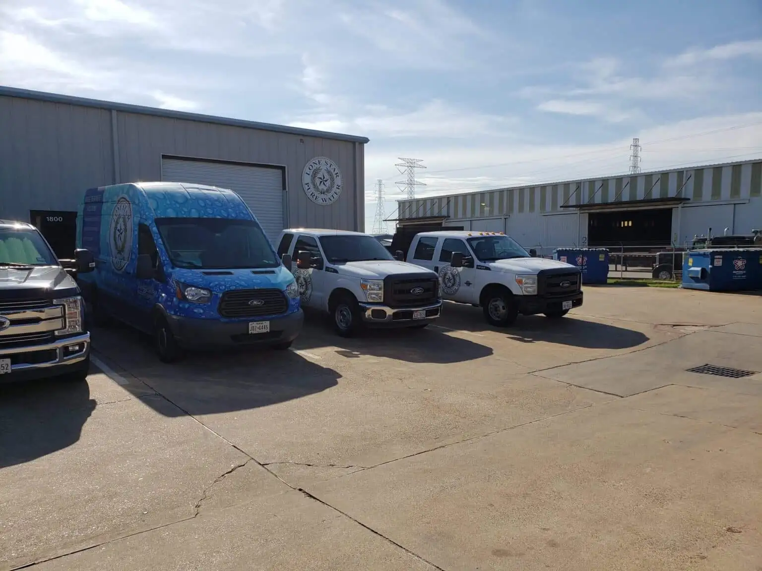Four utility vehicles parked near warehouse.