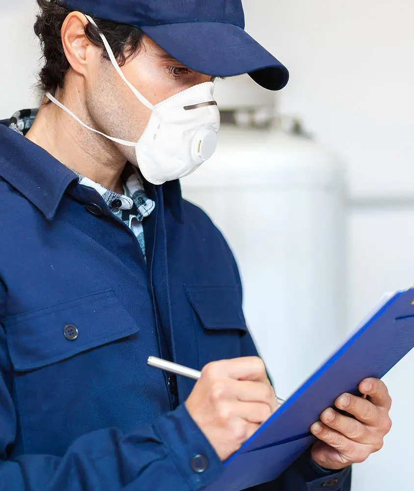 Worker wearing mask writing on clipboard.