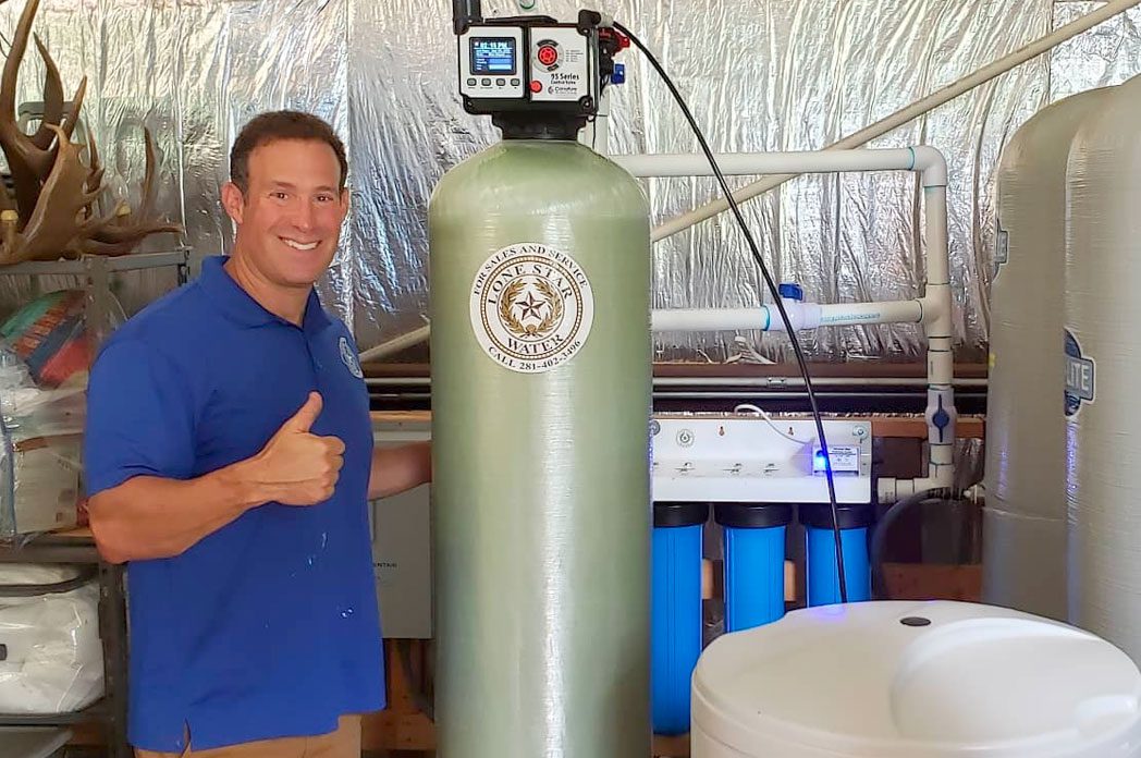 A man standing near lone star water filtration machine