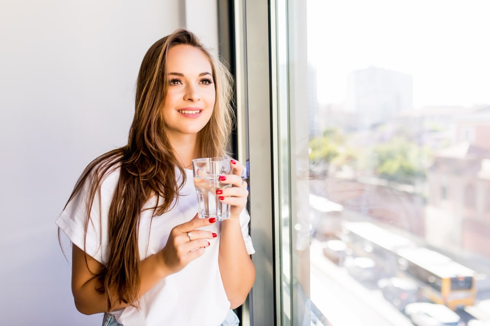 Woman holding a glass of water, highlighting the importance of water filtration systems in homes