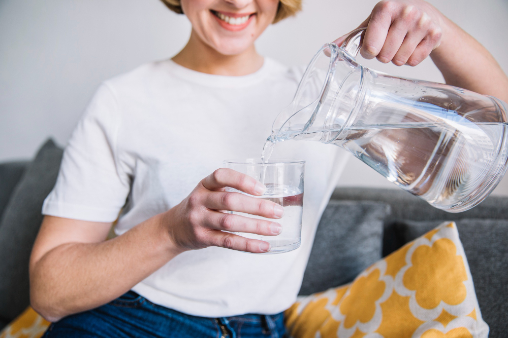 Woman pouring water from a pitcher into a glass, illustrating water quality improvement with a water softener.