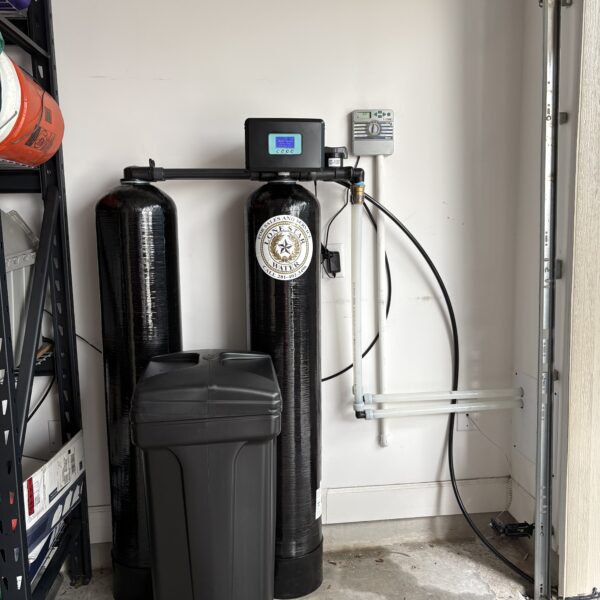 Installed water softener system with control panel and tanks in a garage corner.